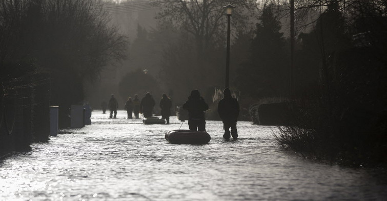 Residents pull boats through a flooded residential street in the UK. Photo: Bloomberg Residents pull boats through a flooded residential street in the UK. Photo: Bloomberg