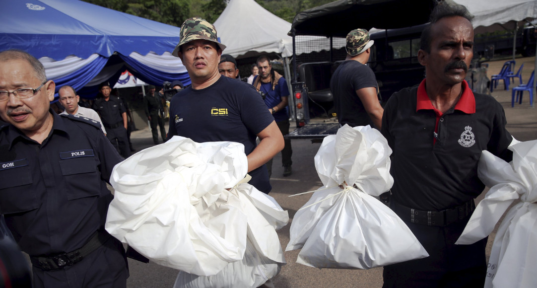 Malaysian policemen carry body bags with human remains found at the site of human trafficking camps near the Thai border. Authorities said on Monday that they found 139 graves in more than two dozen camps. Photo: Reuters Malaysian policemen carry body bags with human remains found at the site of human trafficking camps near the Thai border. Authorities said on Monday that they found 139 graves in more than two dozen camps. Photo: Reuters