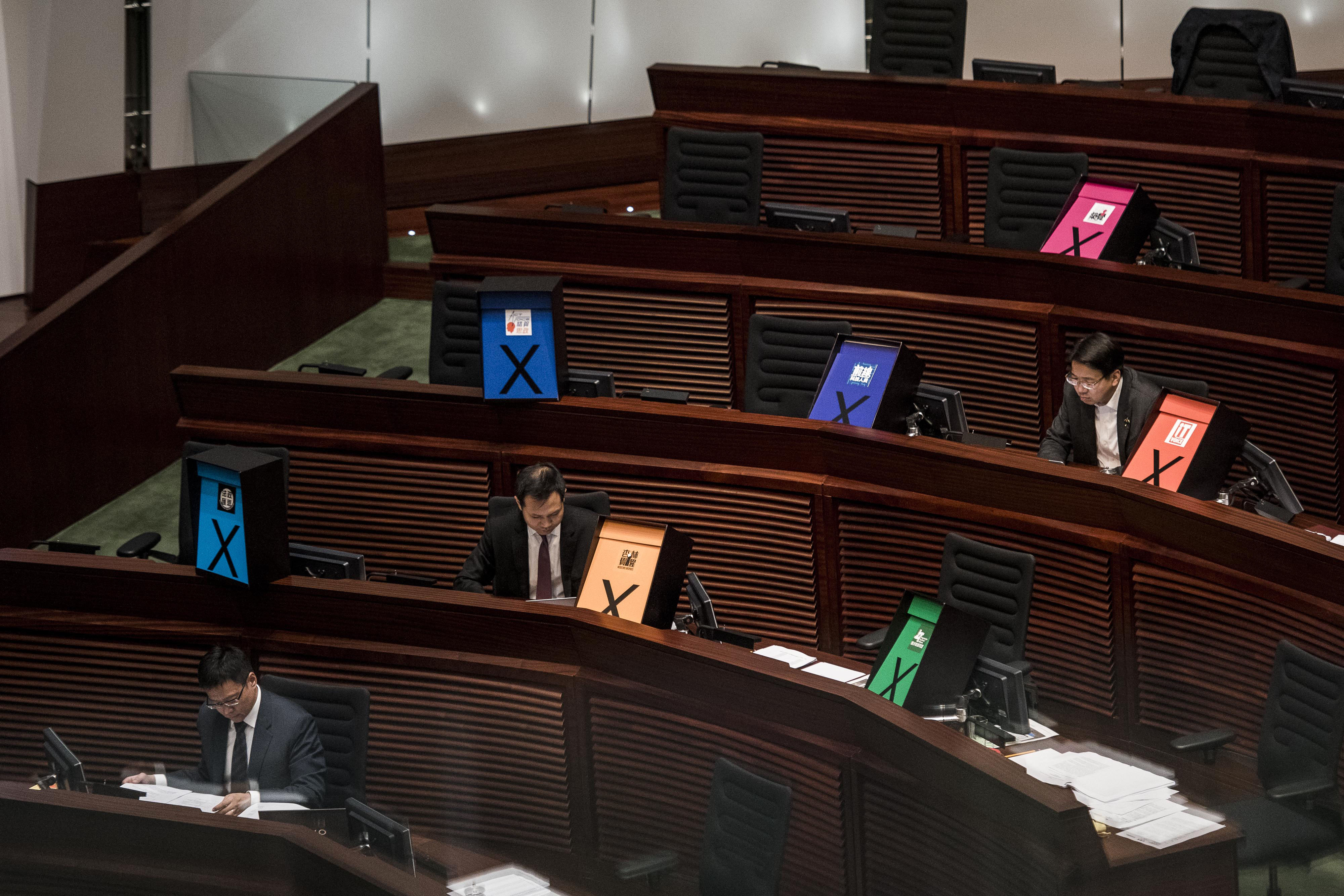 Pro-democracy legislators sit next to signs displaying an "X" to symbolize their rejection of the proposal. Photo: Bloomberg Pro-democracy legislators sit next to signs displaying an "X" to symbolize their rejection of the proposal. Photo: Bloomberg