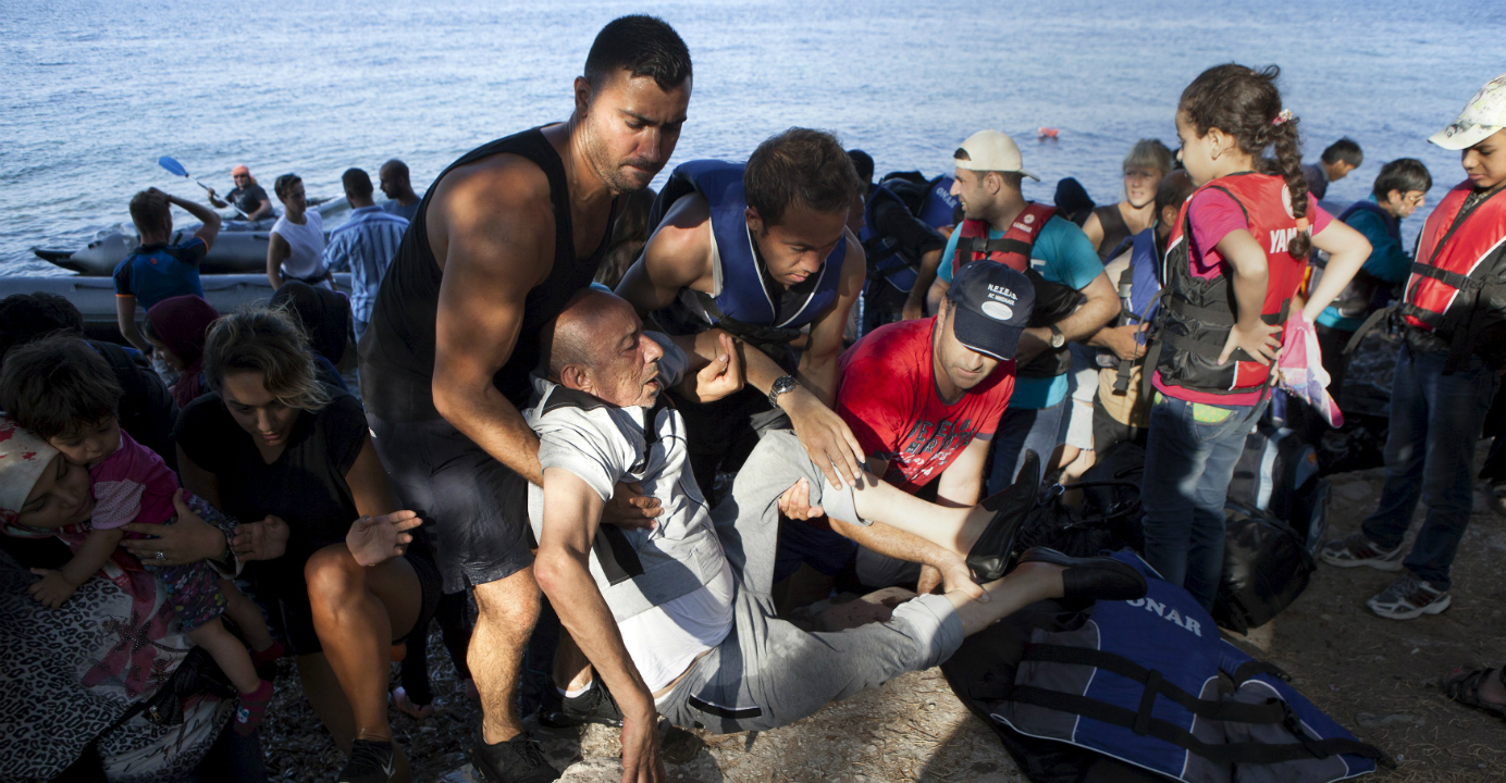 A Syrian refugee is helped by rescuers after arriving on a dinghy on the Greek island of Lesbos. Greece has asked the European Union for aid to prevent it being overwhelmed by refugees. Photo: Reuters A Syrian refugee is helped by rescuers after arriving on a dinghy on the Greek island of Lesbos. Greece has asked the European Union for aid to prevent it being overwhelmed by refugees. Photo: Reuters