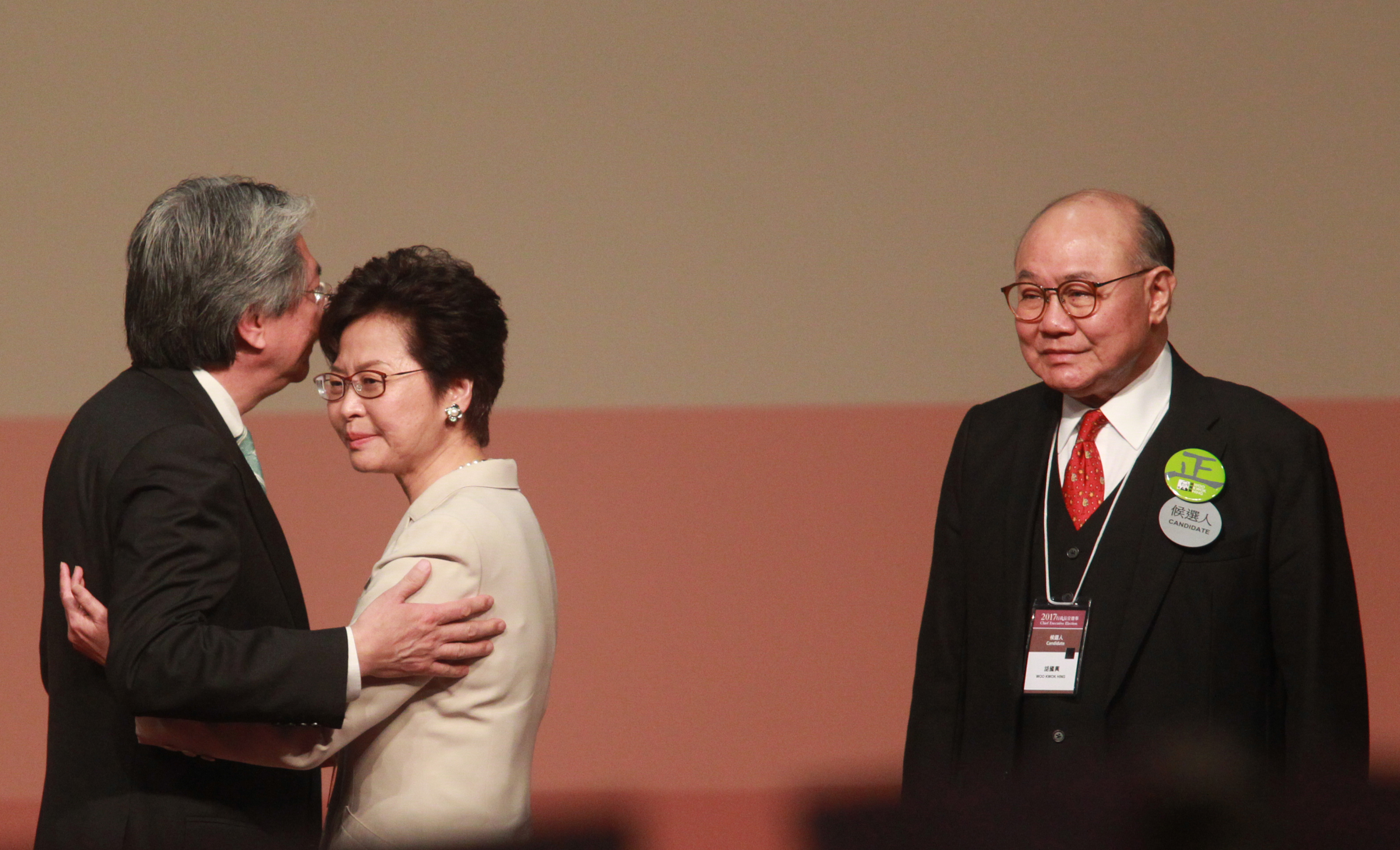 All's well: John Tsang (left) hugs Carrie Lam as Woo Kwok-hing looks on after the voting on Sunday. Photo: HKEJ All's well: John Tsang (left) hugs Carrie Lam as Woo Kwok-hing looks on after the voting on Sunday. Photo: HKEJ