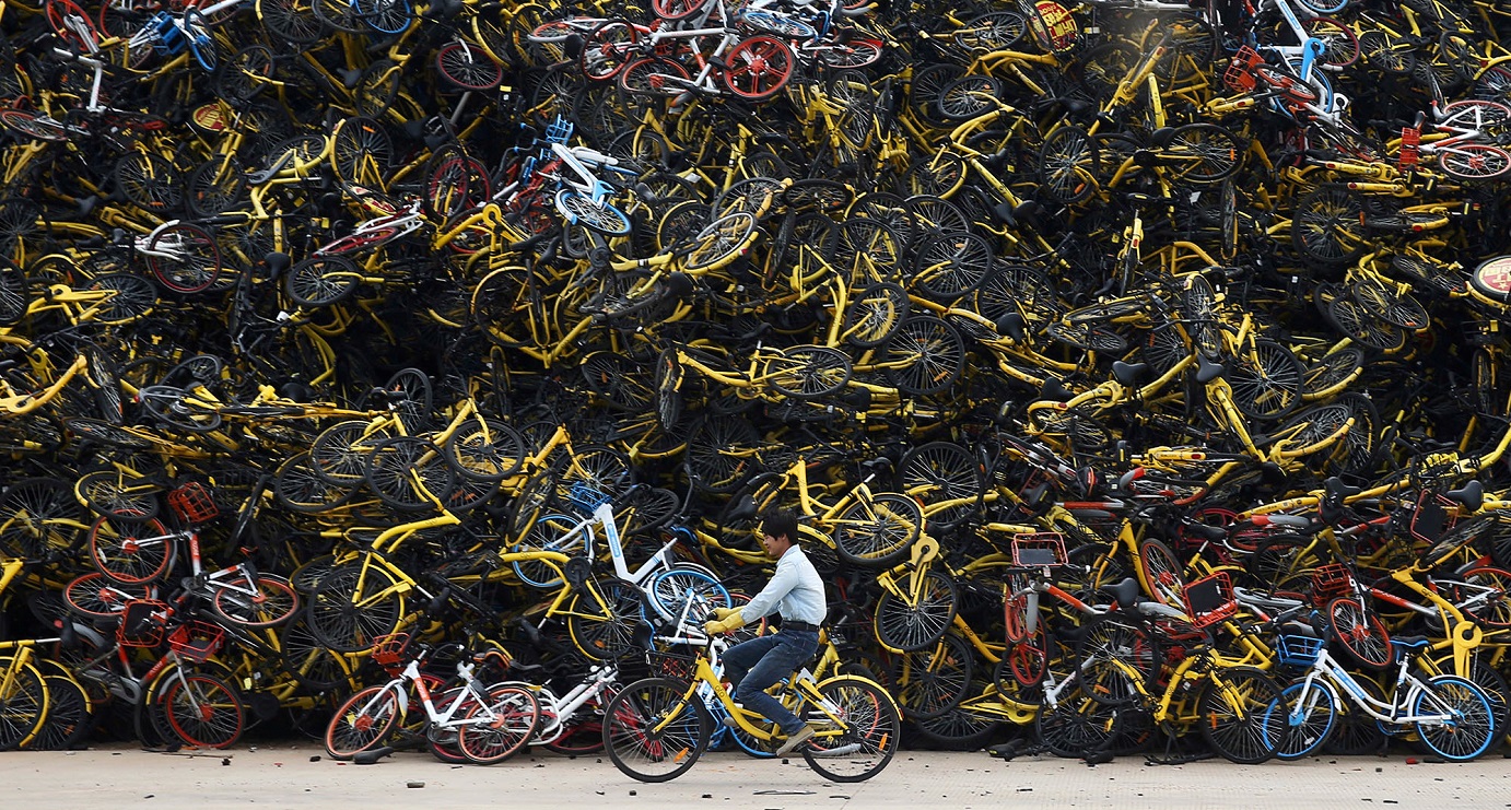 A worker rides a shared bicycle past a huge pile of unused bikes in a vacant lot in China. The market has seen several fast-growing Chinese bike-sharing startups going bust in 2018. Photo: Reuters A worker rides a shared bicycle past a huge pile of unused bikes in a vacant lot in China. The market has seen several fast-growing Chinese bike-sharing startups going bust in 2018. Photo: Reuters