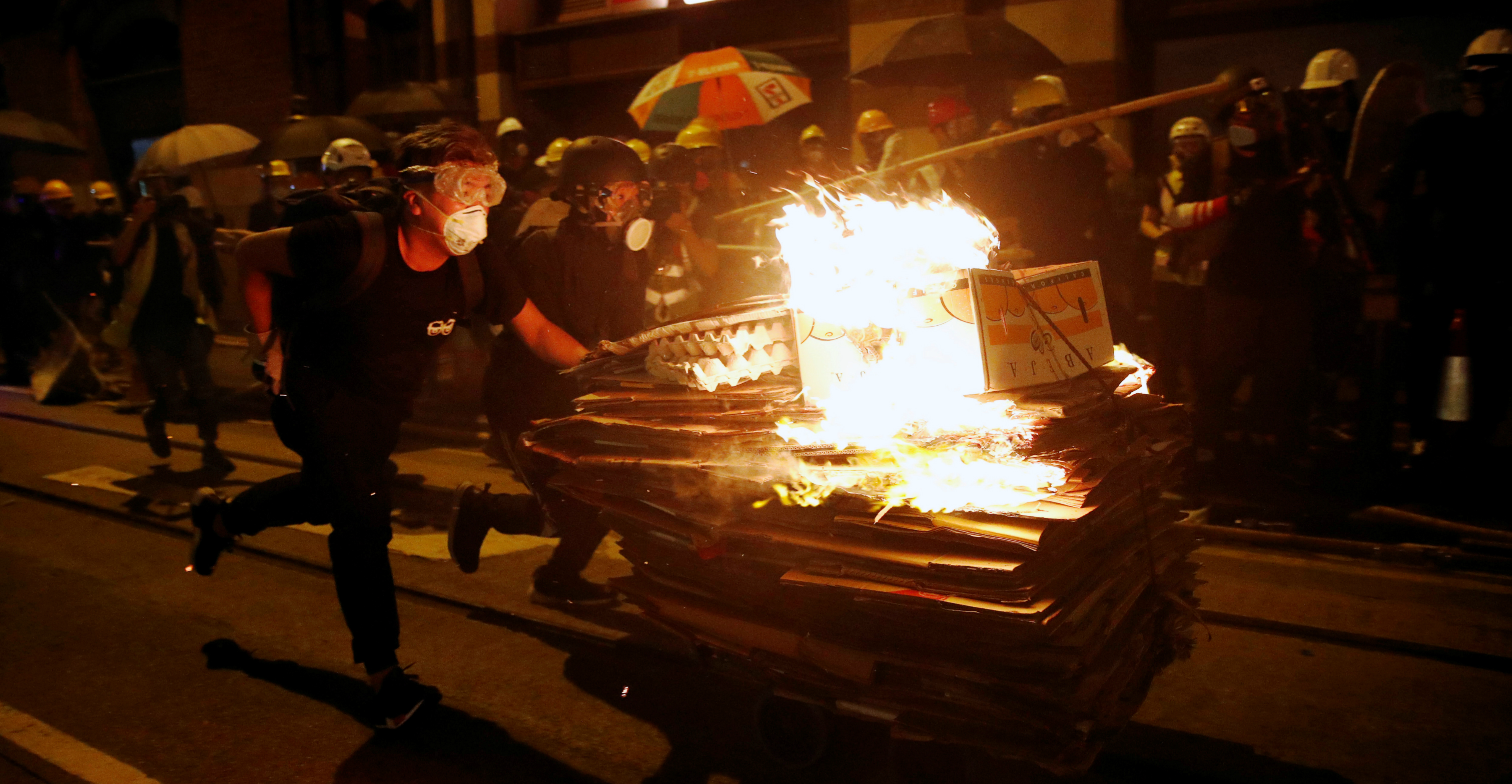 Demonstrators charge with a cart filled with burning cardboard during a clash with police in Sheung Wan on Sunday. Photo: Reuters Demonstrators charge with a cart filled with burning cardboard during a clash with police in Sheung Wan on Sunday. Photo: Reuters