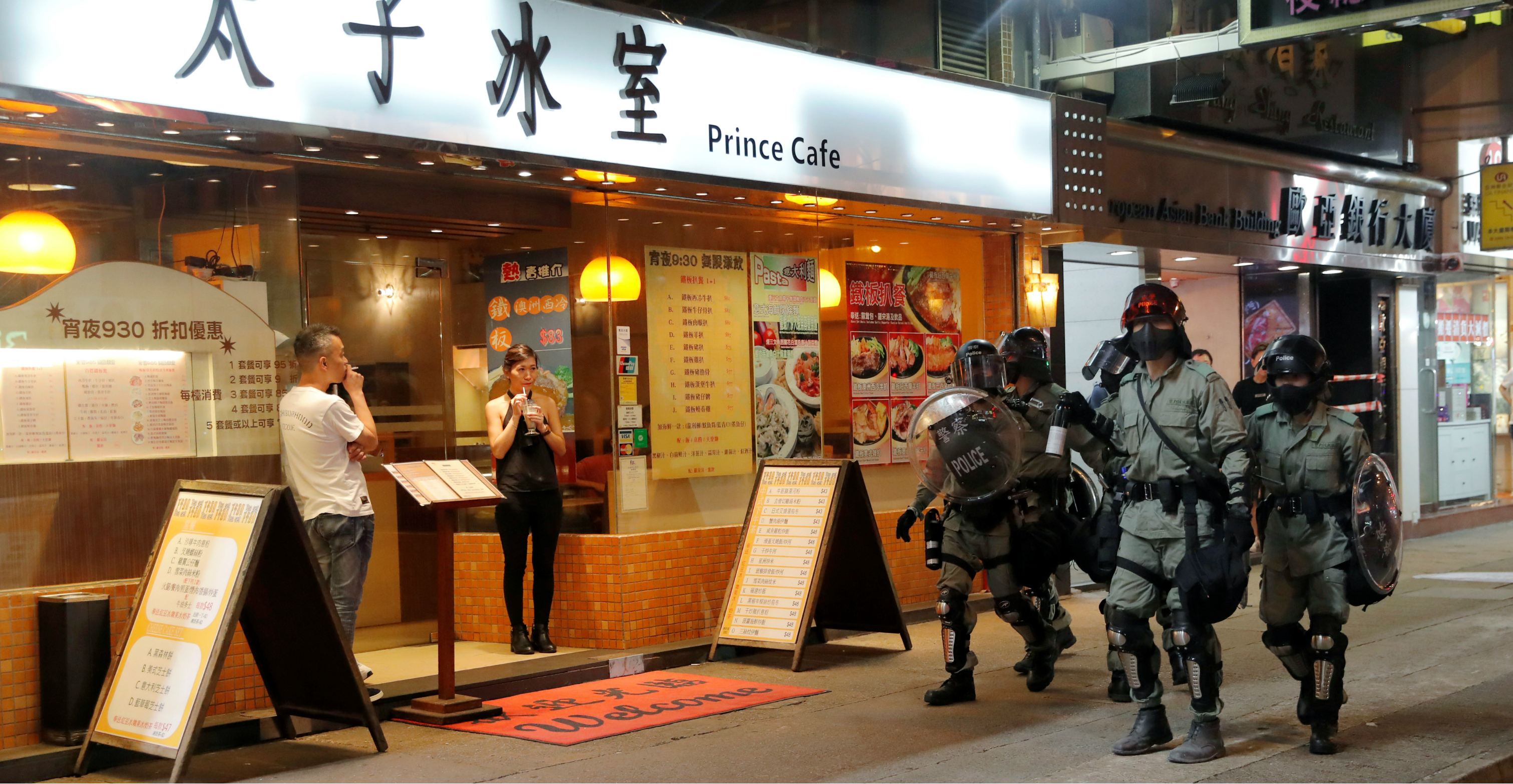 People standing outside a restaurant look on as riot police search for anti-government protesters in Mong Kok on Monday. Photo: Reuters People standing outside a restaurant look on as riot police search for anti-government protesters in Mong Kok on Monday. Photo: Reuters