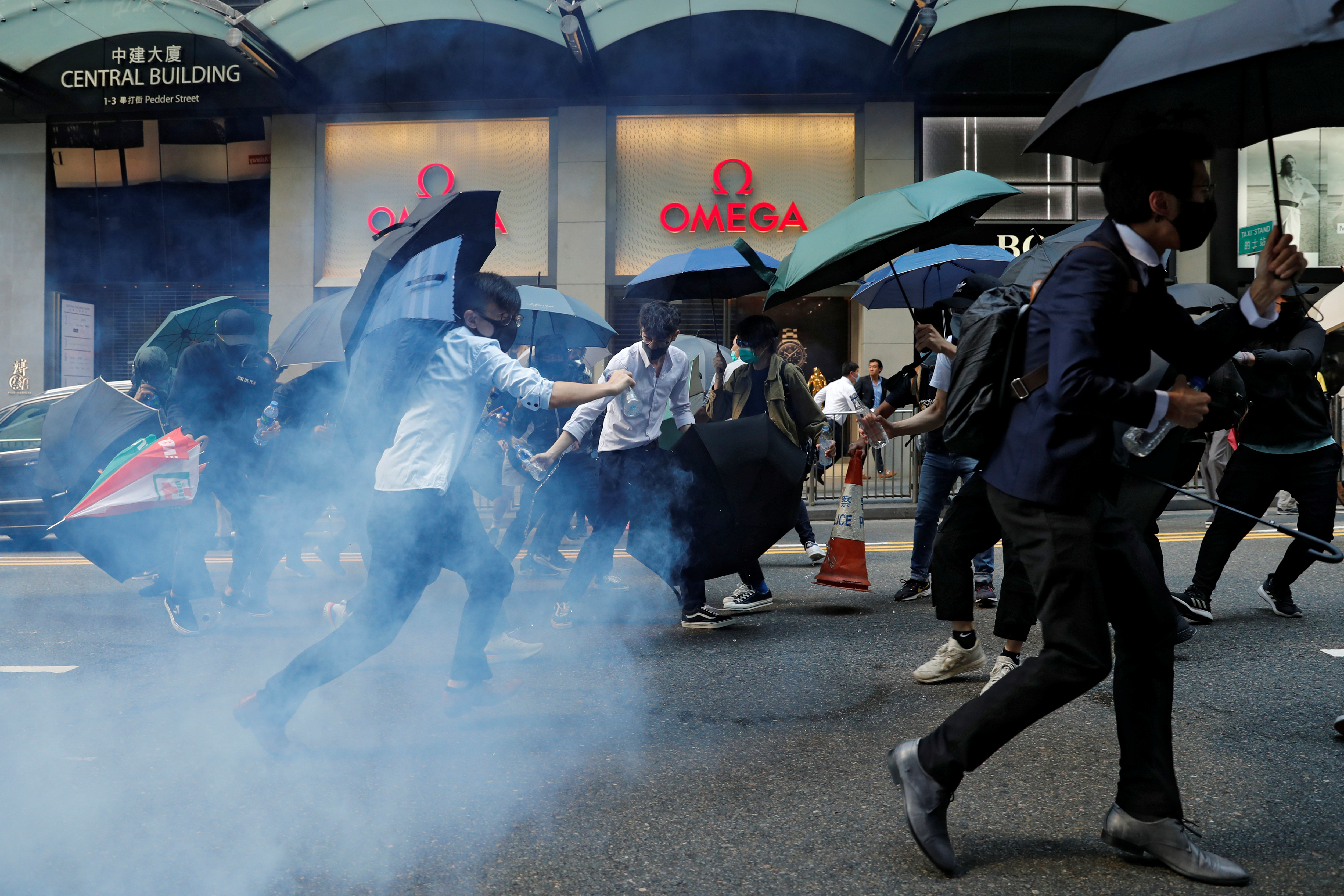 Office workers run away from tear gas as they attend a flash mob anti-government protest in Hong Kong’s Central district on Monday. Photo: Reuters Office workers run away from tear gas as they attend a flash mob anti-government protest in Hong Kong’s Central district on Monday. Photo: Reuters