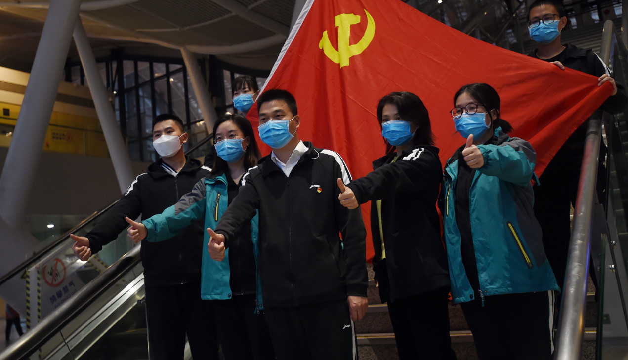 Medical workers from outside Wuhan pose for pictures with a Chinese Communist Party flag at the Wuhan railway station before leaving the city on March 17. China and the US have been engaging in a war or words in relation to the Covid-19 outbreak. Photo: R Medical workers from outside Wuhan pose for pictures with a Chinese Communist Party flag at the Wuhan railway station before leaving the city on March 17. China and the US have been engaging in a war or words in relation to the Covid-19 outbreak. Photo: R