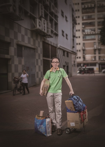 香港大學醫學院院長梁卓偉解下領帶穿上速遞員制服。（謝至德攝影作品） 
除了藝術家作品，樂施會還找來幾位名人，包括Cue后吳安儀、足球教練「牛丸」陳婉婷、導演黃修平、香港大學醫學院院長梁卓偉扮成清潔、速遞員等等，試工大半天，由謝志德拍成攝影作品《有名有姓》。